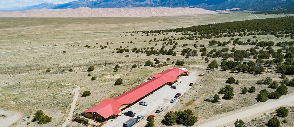 Exterior shot of the Lodge from a long range, showcasing the mountains in the distance, the plains inbetween, and the lodge property. 