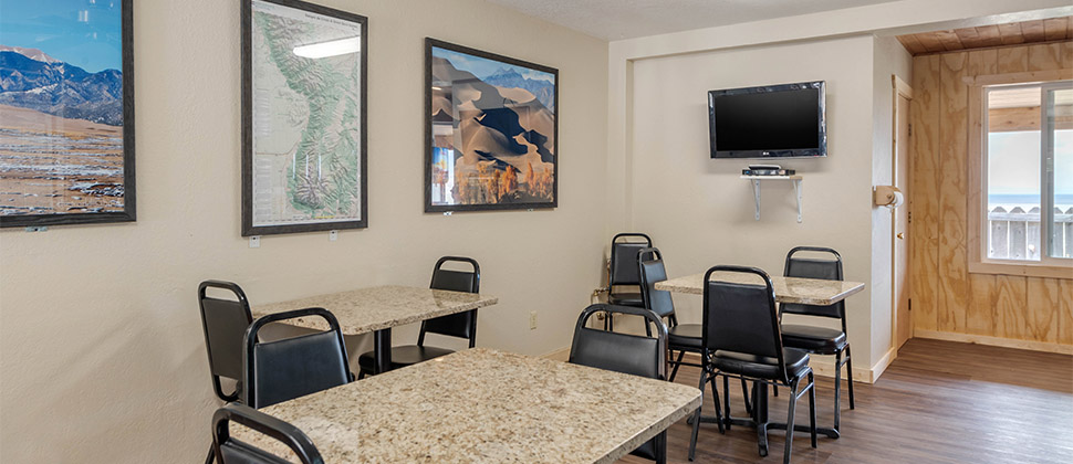 An interior dining area with chairs, granite tables, and artwork on the walls create a cozy dining area. 