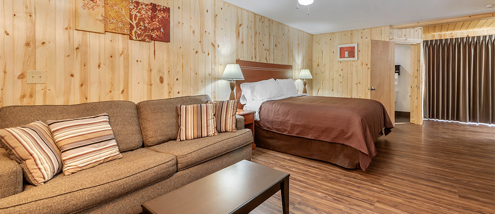 A sitting area with sofa and coffee table next to the bed. Matching lamps sit on bedside tables on either side of the bed. 