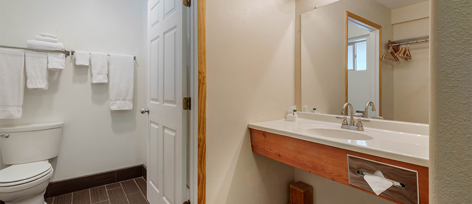 A wall mounted sink with full size mirror. Door opens into the commode. 