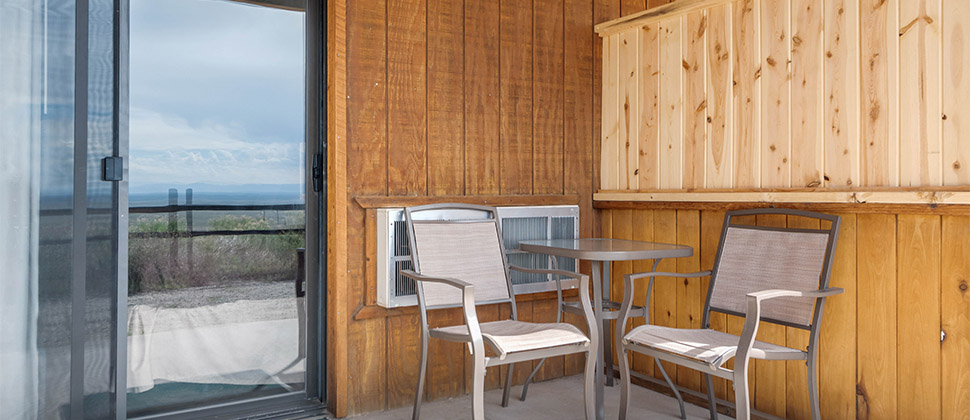 Outdoor patio chairs set into a small nook, with the entry way mostly visible opposite the chairs. 