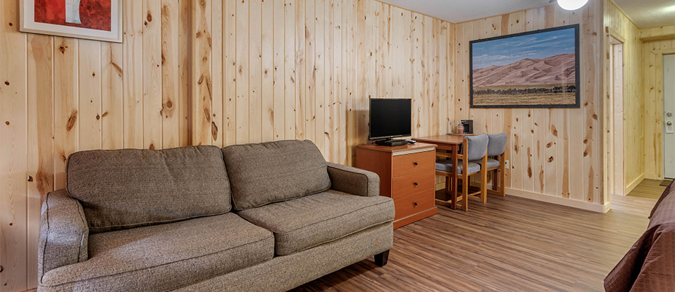 A cozy sitting area opposite the bed with sofa, television, and sitting area. 