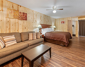 A bedroom as viewed through an open wall sitting area, with the vantage point being just over a coffee table in the center of the room.