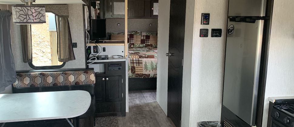 View of dining area next to window with light above, kitchen with stainless steel appliances and view of bedroom